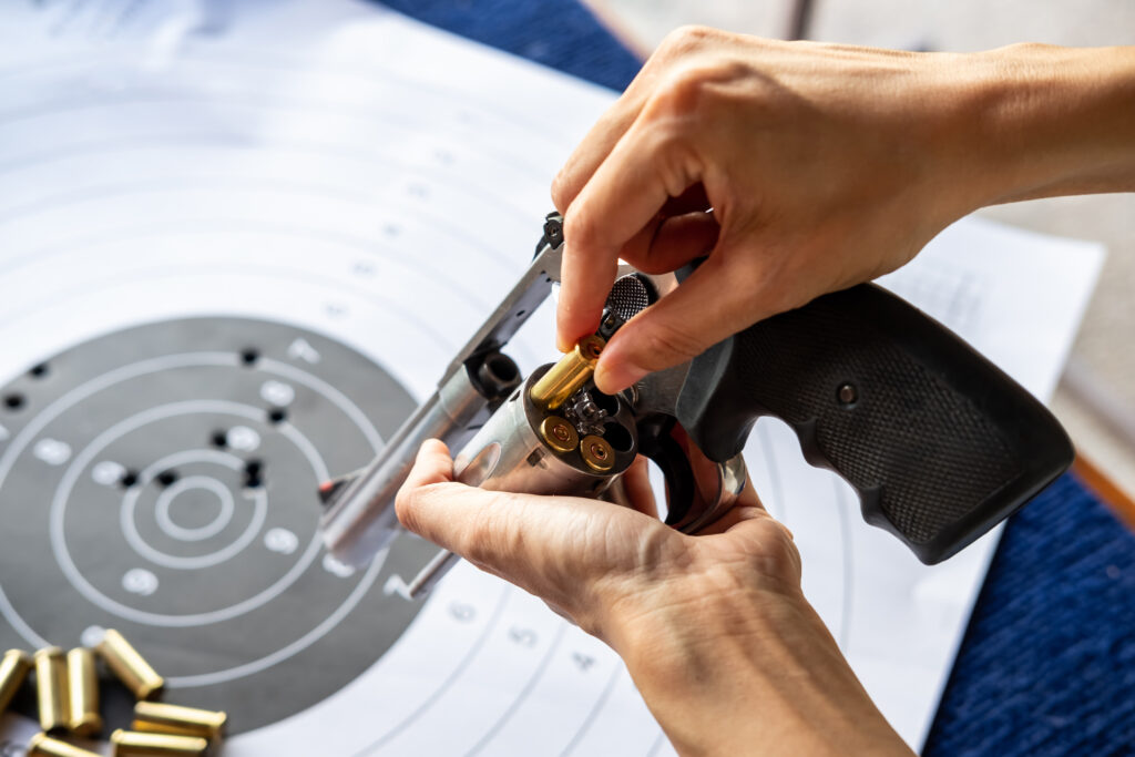 woman's hand reloading pistol revolver with bullets and target