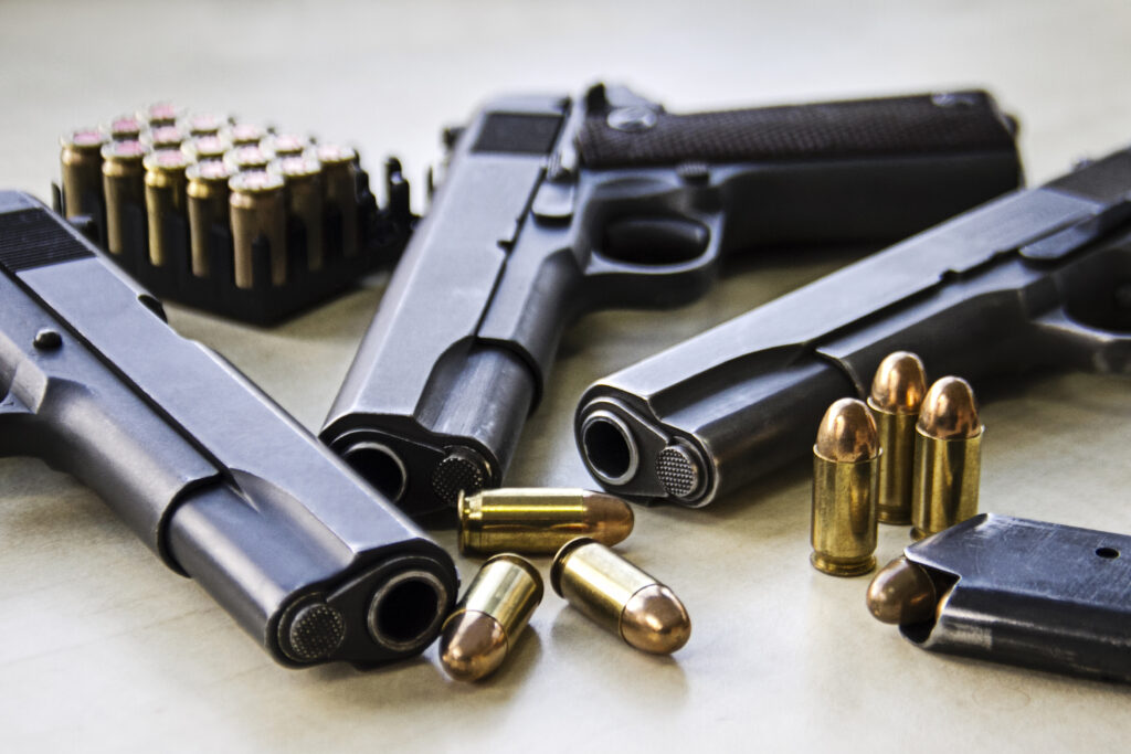 Three pistols laying on table with bullets